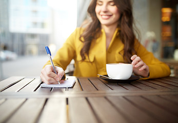 Image showing happy woman with notebook and cappucino at cafe