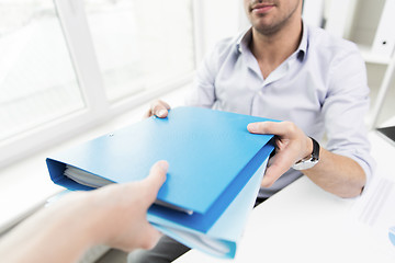 Image showing close up of businessman taking folders from hand