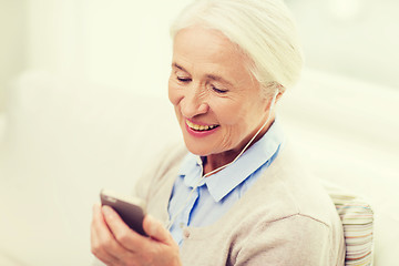 Image showing senior woman with smartphone and earphones at home