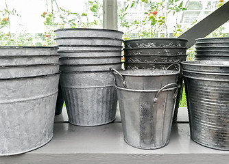 Image showing Simple metal flower pots on a shelf