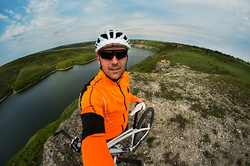 Image showing Cyclist in Orange Wear Riding the Bike above River