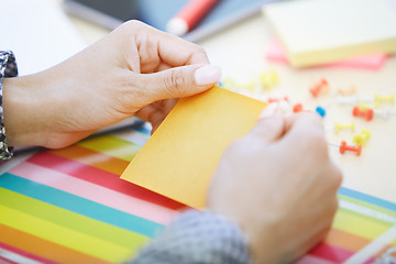 Image showing Woman at office holding adhesive note