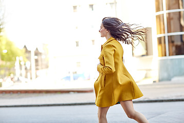 Image showing happy young woman running along on city street