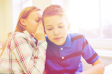 Image showing smiling schoolgirl whispering to classmate ear