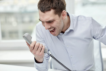 Image showing furious businessman calling on phone in office