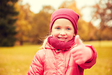 Image showing happy little girl showing thumbs up in autumn park