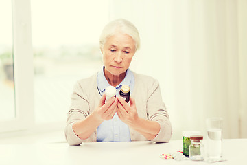 Image showing senior woman with medicine jars at home