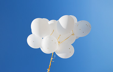 Image showing close up of white helium balloons in blue sky