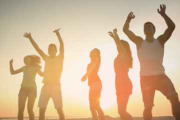 Image showing smiling friends dancing on summer beach