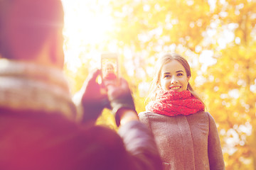 Image showing smiling couple with smartphone in autumn park