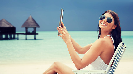 Image showing smiling woman with tablet pc sunbathing on beach