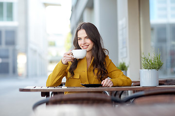 Image showing happy woman drinking cocoa at city street cafe