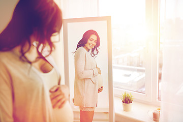 Image showing happy pregnant woman looking to mirror at home