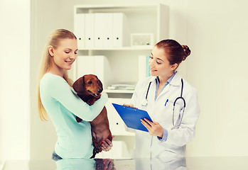 Image showing happy woman with dog and doctor at vet clinic