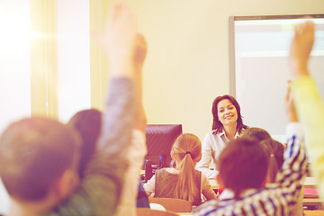 Image showing group of school kids raising hands in classroom