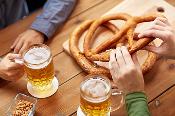 Image showing close up of men drinking beer with pretzels at pub