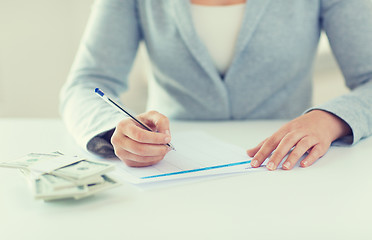 Image showing close up of hands with money filling tax form