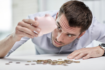 Image showing businessman with piggy bank and coins at office