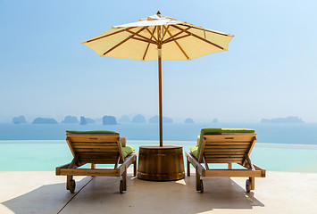 Image showing infinity pool with parasol and sun beds at seaside