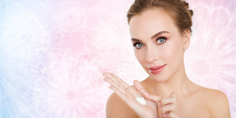 Image showing happy young woman with moisturizing cream on hand