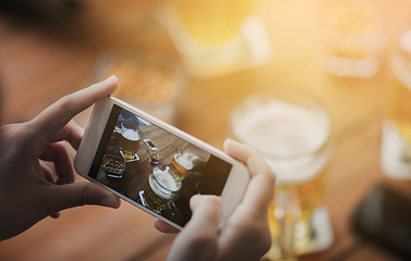 Image showing close up of hands with smartphone picturing beer