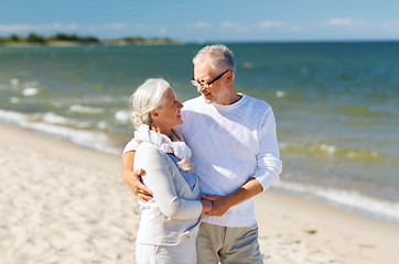 Image showing happy senior couple holding hands on summer beach