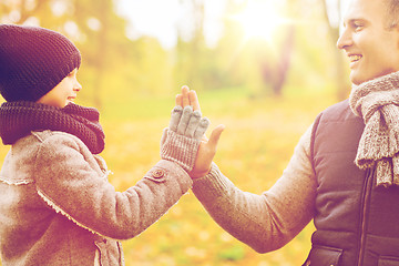 Image showing happy father and son making high five in park