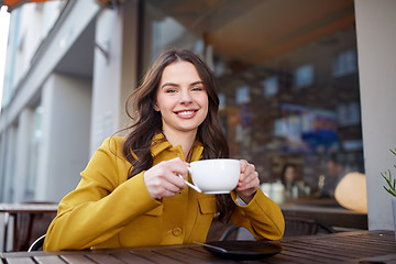 Image showing happy woman drinking cocoa at city street cafe