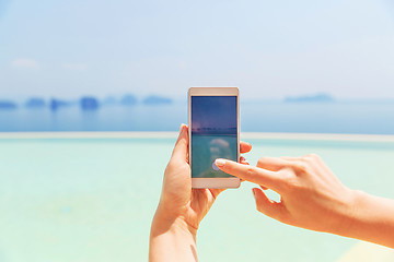 Image showing close up of female hand with smartphone on beach