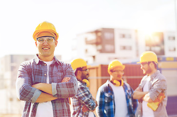 Image showing group of smiling builders in hardhats outdoors