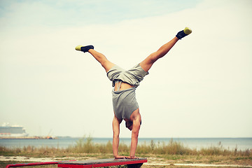 Image showing young man exercising on bench outdoors