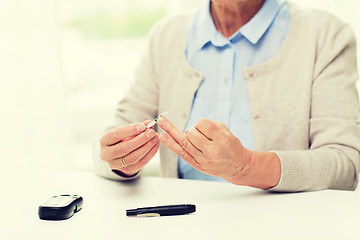 Image showing senior woman with glucometer checking blood sugar