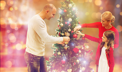 Image showing smiling family decorating christmas tree at home