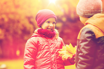 Image showing little boy giving autumn maple leaves to girl