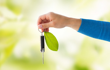 Image showing close up of hand holding car key with green leaf