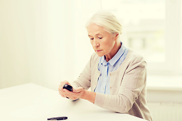 Image showing senior woman with glucometer checking blood sugar