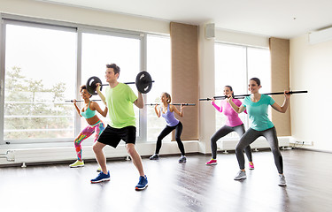 Image showing happy people exercising with barbell bars in gym