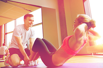 Image showing woman with personal trainer doing sit ups in gym