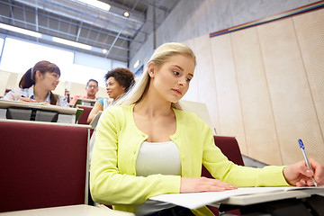 Image showing student girl writing to notebook at lecture hall