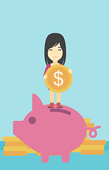 Image showing Business woman putting coin in piggy bank.