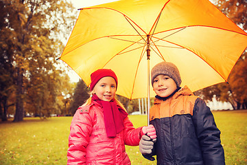 Image showing happy boy and girl with umbrella in autumn park