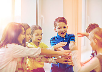 Image showing group of smiling school kids putting hands on top