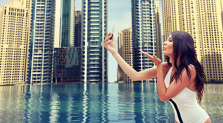 Image showing woman taking selfie with smartphone over city pool