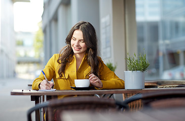 Image showing happy woman with notebook drinking cocoa at cafe