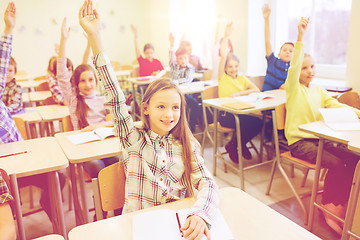 Image showing group of school kids raising hands in classroom