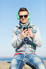 Image showing happy young man in headphones with smartphone