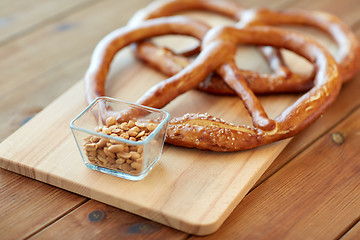 Image showing close up of peanuts and pretzels on wooden table