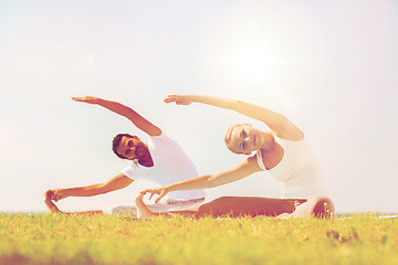 Image showing smiling couple making yoga exercises outdoors