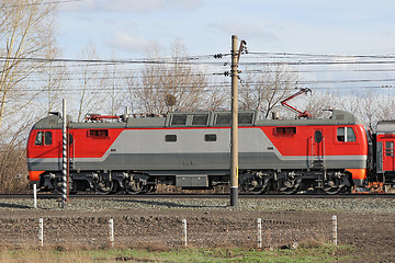 Image showing Red locomotive on electricity coming by rail.