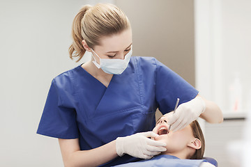 Image showing female dentist checking patient girl teeth